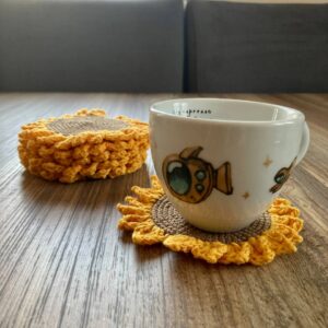 Una taza de café y Posavasos de girasoles sobre una mesa de madera.