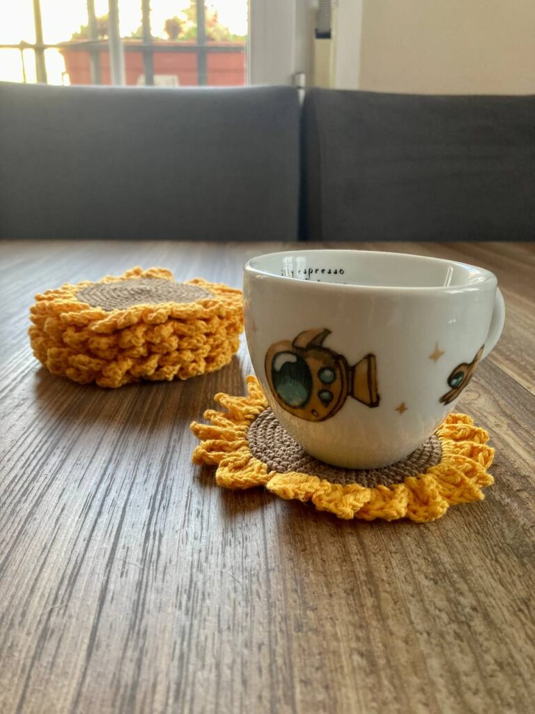 Una taza de café y Posavasos de girasoles sobre una mesa de madera.