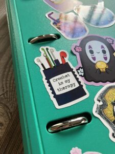 Pegatina con el texto crochet is my therapy sobre una carpeta verde